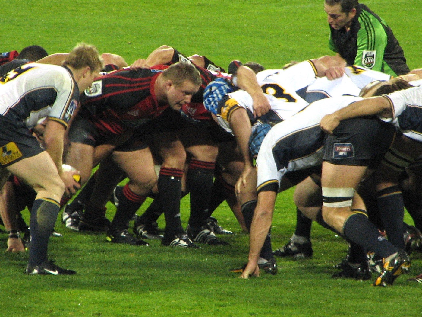 A rugby union scrum: two packs of forwards bound together, heads down, pushing as one unit.
