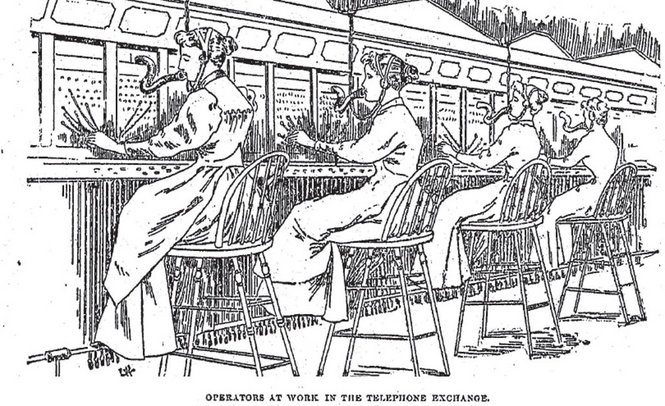 Two women working as telephone switchboard operators in 1893, plugging cables into a large wall-mounted exchange board.