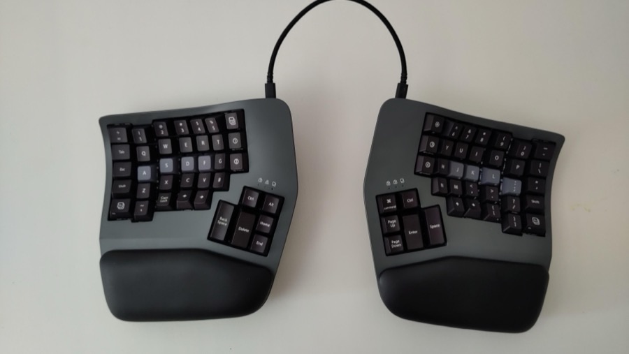 A Kinesis Advantage360 keyboard, split into two separate, identically-shaped halves connected by a coiled cable.